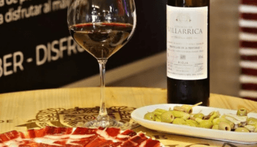 Copa de vino tinto español maridada con ración de jamón ibérico