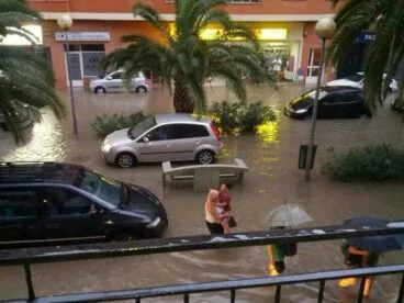 Un coche circula sobre el Paseo del Saladar de Dénia durante la tormenta