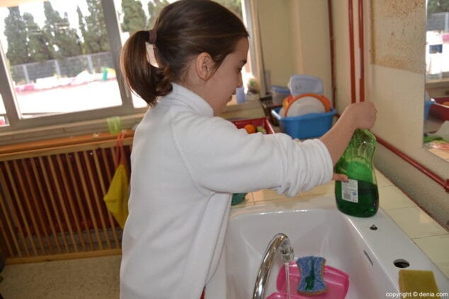 15 Lucía fregando su recipiente del almuerzo