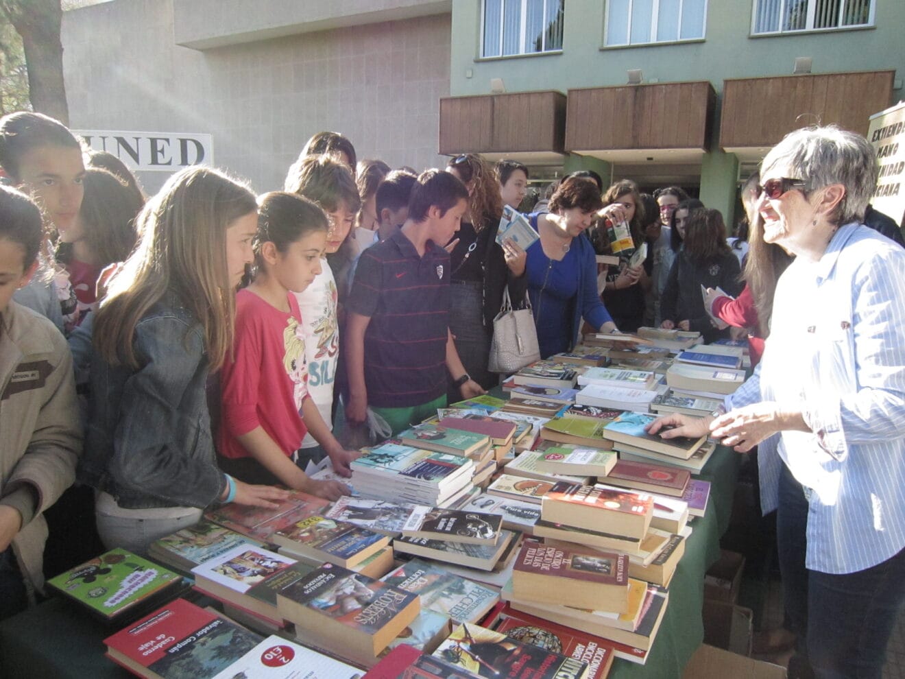 Escolares en la mesa de intercambio un libro por comida de la UNED Dénia