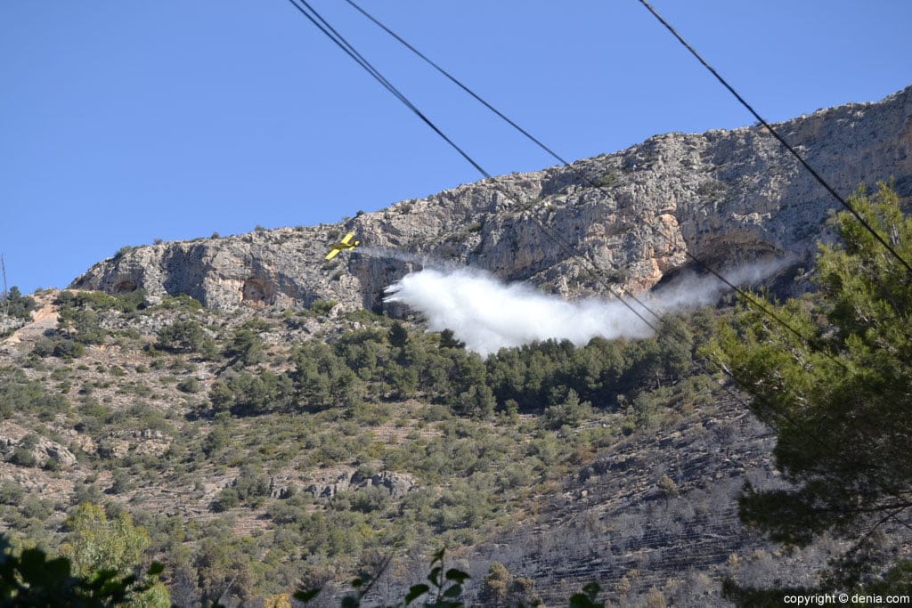 Una avioneta descargando agua sobre la zona incendiada