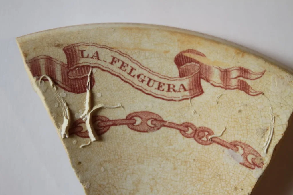 Inscripción de La Felguera en un fragmento de loza