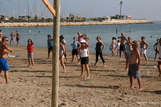 De todas las edades van a las clases de deporte en la playa