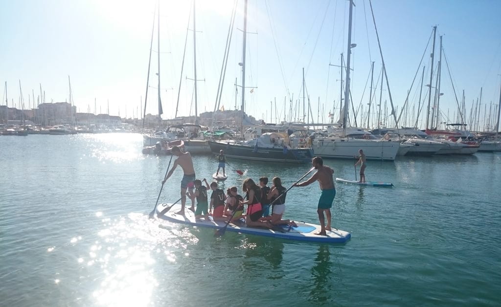 Grupo de niños sobre una tabla de Paddle Surf en el puerto de Dénia