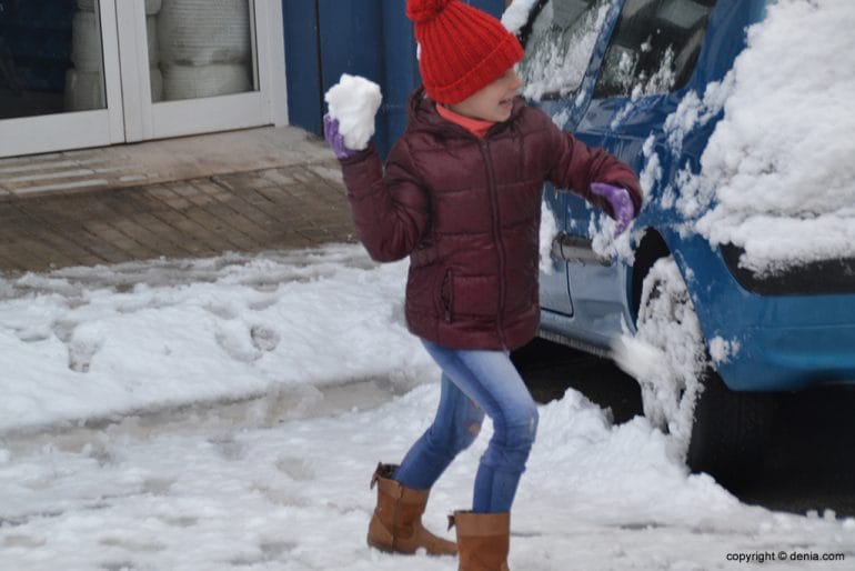Niña lanzando bola de nieve