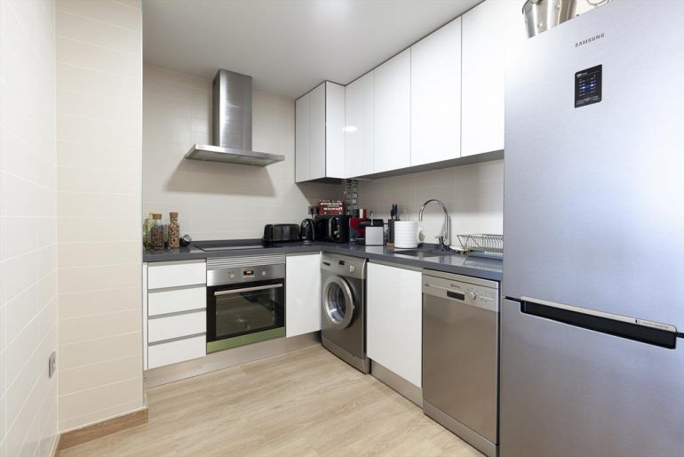 Cocina abierta con electrodomésticos modernos en apartamento de alquiler - Quality Rent a Villa