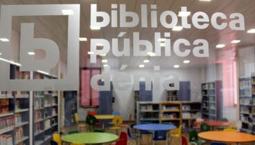 Logotipo de la Biblioteca de Dénia impreso en el cristal que separa el hall de la sala infantil