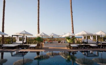 Piscina rodeada de parasoles y hamacas en Purobeach Dénia