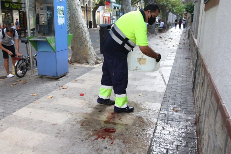 O pessoal de limpeza limpa o sangue da rua