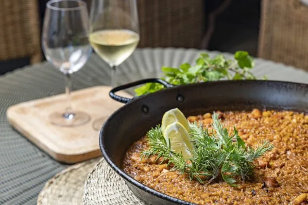 Dónde comer paella en Dénia: restaurantes y contacto para reservar 6 Imagen: Saborear un arroz a banda en Dénia con un vino blanco