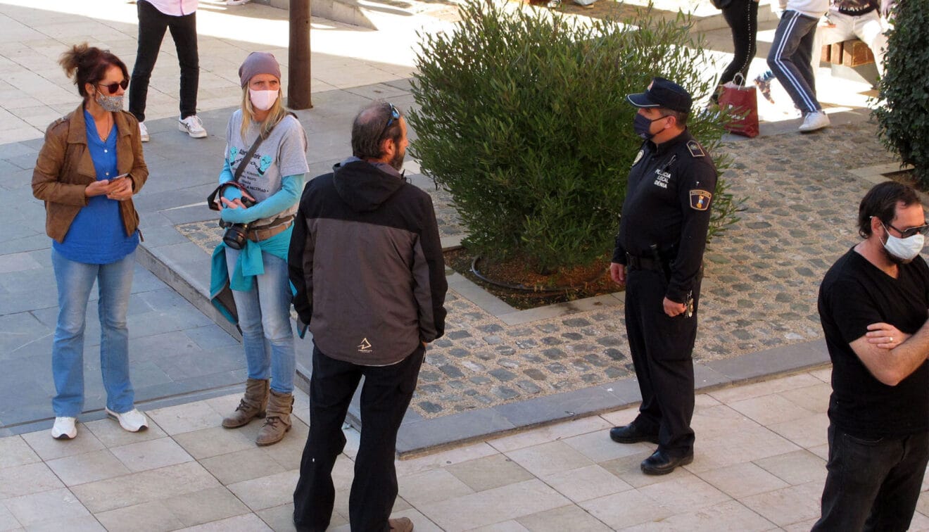 Agente de la policía llamando la atención a un hombre sin mascarilla frente al ayuntamiento