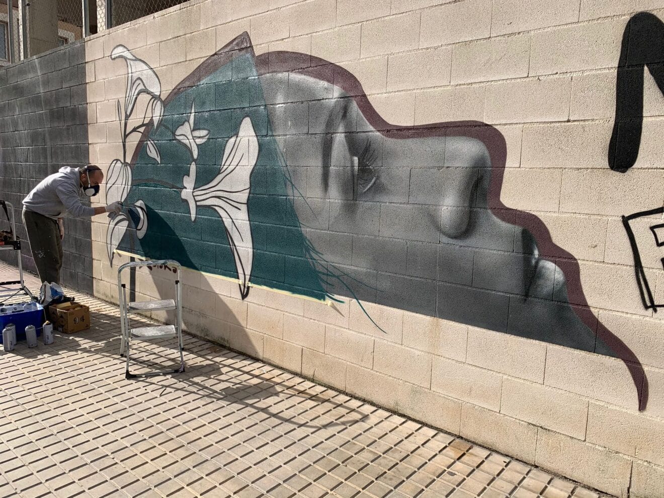Artista arreglando un mural víctima de actos vandálicos
