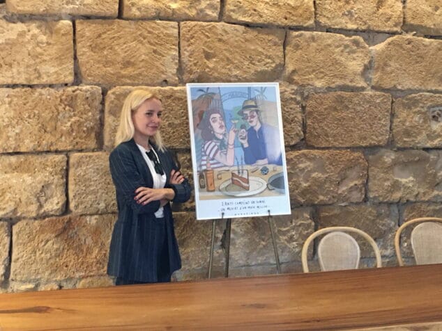 Imagen: Carla Fuentes junto a su ilustración por el aniversario de Els Magazinos