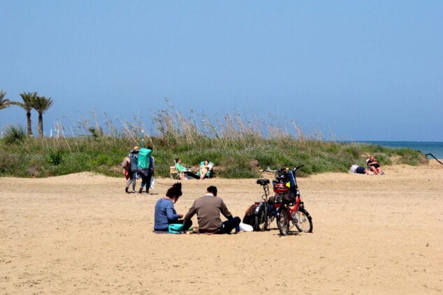 Familias disfrutando del día de Pascua en la extensa arena de la playa de Les Marines en Dénia.
