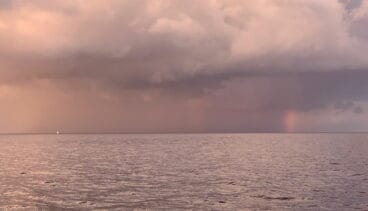 Un velero hacia el arcoíris en el horizonte