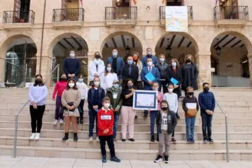 Componentes del CLIA sostienen el diploma junto a los miembros de la corporación municipal y los representantes de UNICEF