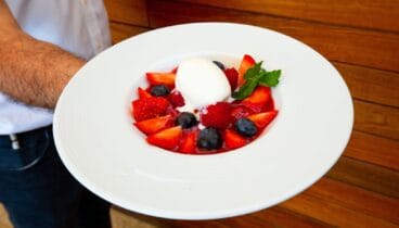 Bola de helado bañado en salsa de frutos rojos, arándanos y fresas