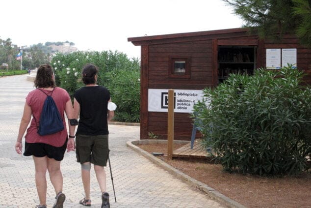 Imagen: Viandantes curiosean la Biblioplatja