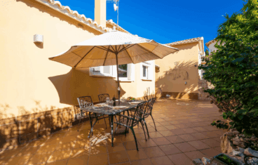 Terraza exterior con mesa y sillas en esta villa disponible con Aguila Rent a Villa