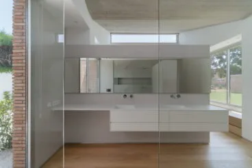 Baño luminoso con paredes de microocemento y muebles del lavabo en color blanco