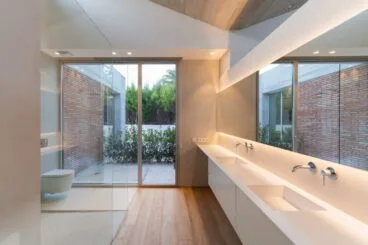 Baño minimalista en colores blancos con dos lavabos