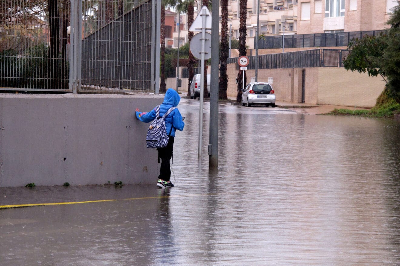 Estudiante intentando llegar al instituto con la calle anegada por la lluvia