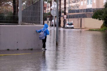 estudiante intentando llegar al instituto con la calle anegada por la lluvia
