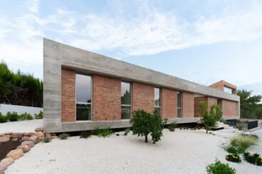 Exterior de la vivienda con jardín de piedras y vegetación