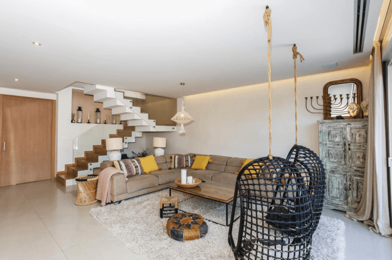 Salón de la villa de estilo boho con sillas colgantes