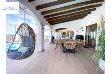 Comedor exterior y silla colgante junto a la piscina