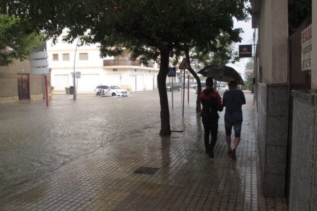 Lluvia en Dénia: ¿hasta cuándo durará el nuevo episodio de precipitaciones? 1 Imagen: Jóvenes paseando bajo el paraguas junto a una avenida anegada de Dénia