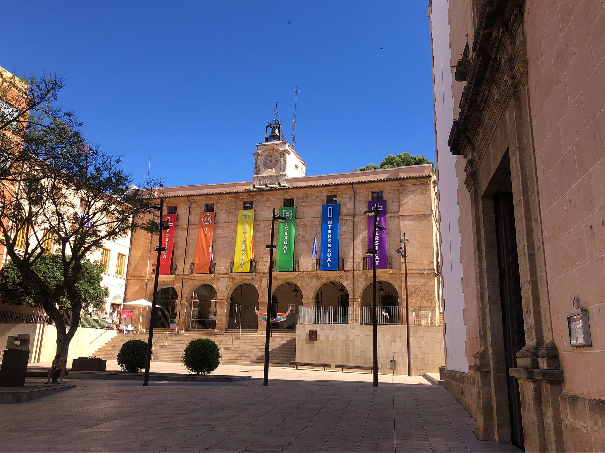 Plaza de la Constitució con el ayuntamiento al fondo decorado por el Día del Orgullo