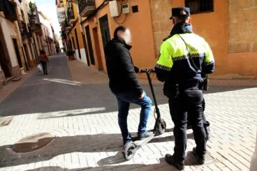 Policía advirtiendo a un usuario de patinete en una peatonal de Dénia