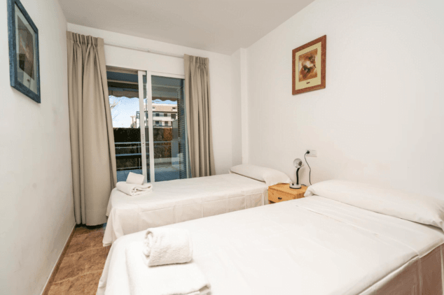 dormitorio con dos camas individuales y acceso a la terraza