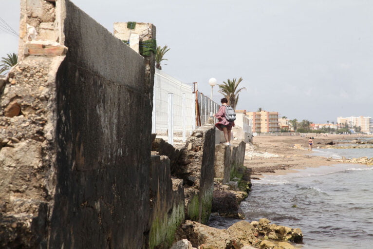 Bañista sorteando los escombros de la inexsistente orilla en una playa de Dénia