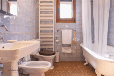 Baño rústico con suelo empedrado y bañera