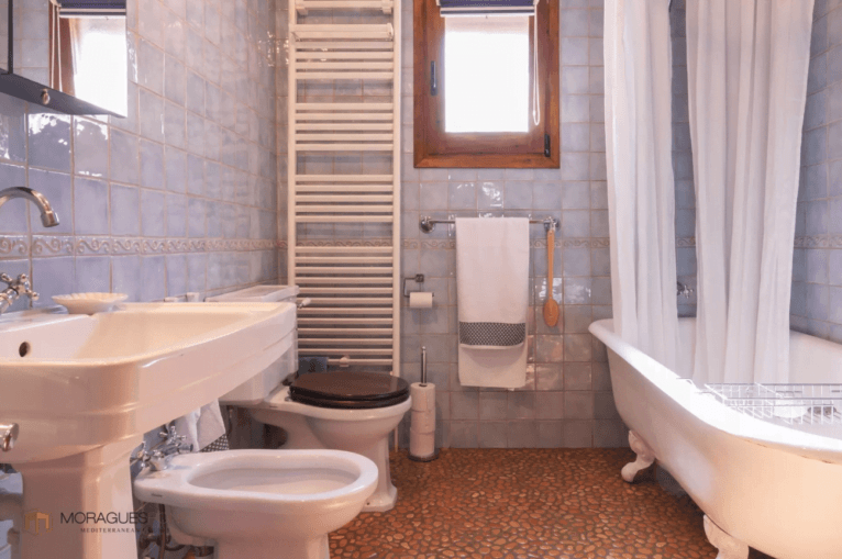 Baño rústico con suelo empedrado y bañera