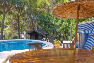 Conjunto de exterior junto a la piscina con sombrillas de mimbre