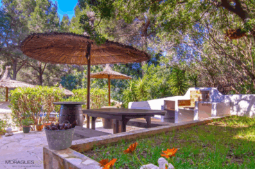 Zona de barbacoa exterior con comedor y sombrilla