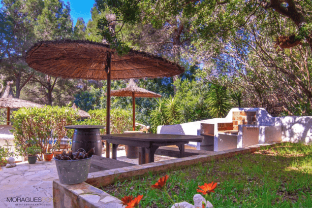 zona de barbacoa exterior con comedor y sombrilla