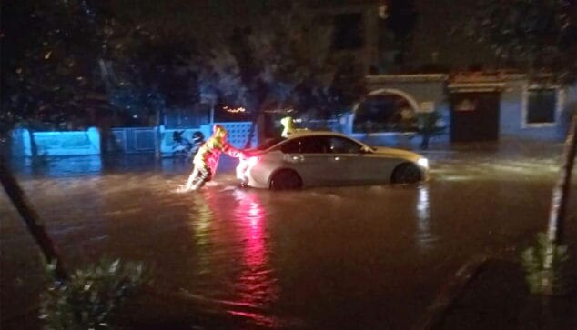 un coche es empujado para sacarlo de una calle inundada de denia