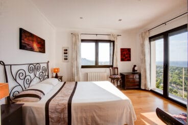 Dormitorio doble con cama de matrimonio con puertas acristaladas