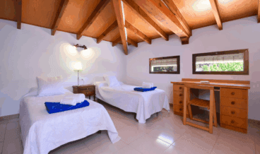 Dormitorio rústico con techo de madera y dos camas individuales