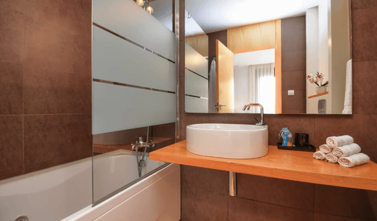 Baño en suite con lavabo ovalado y bañera-ducha