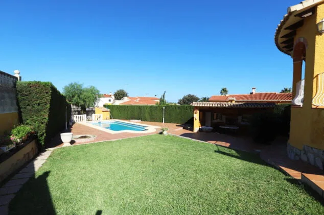 amplio jardin con cesped junto a la piscina