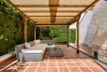 Comedor exterior con sofás de mimbre y pérgola