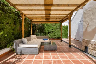 Comedor exterior con sofás de mimbre y pérgola