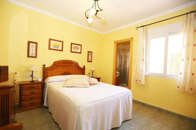 dormitorio principal con cama doble y bancc83o en suite