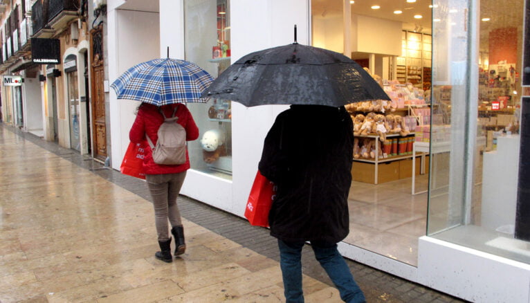 Gente paseando con paraguas bajo la lluvia en el centro de Dénia