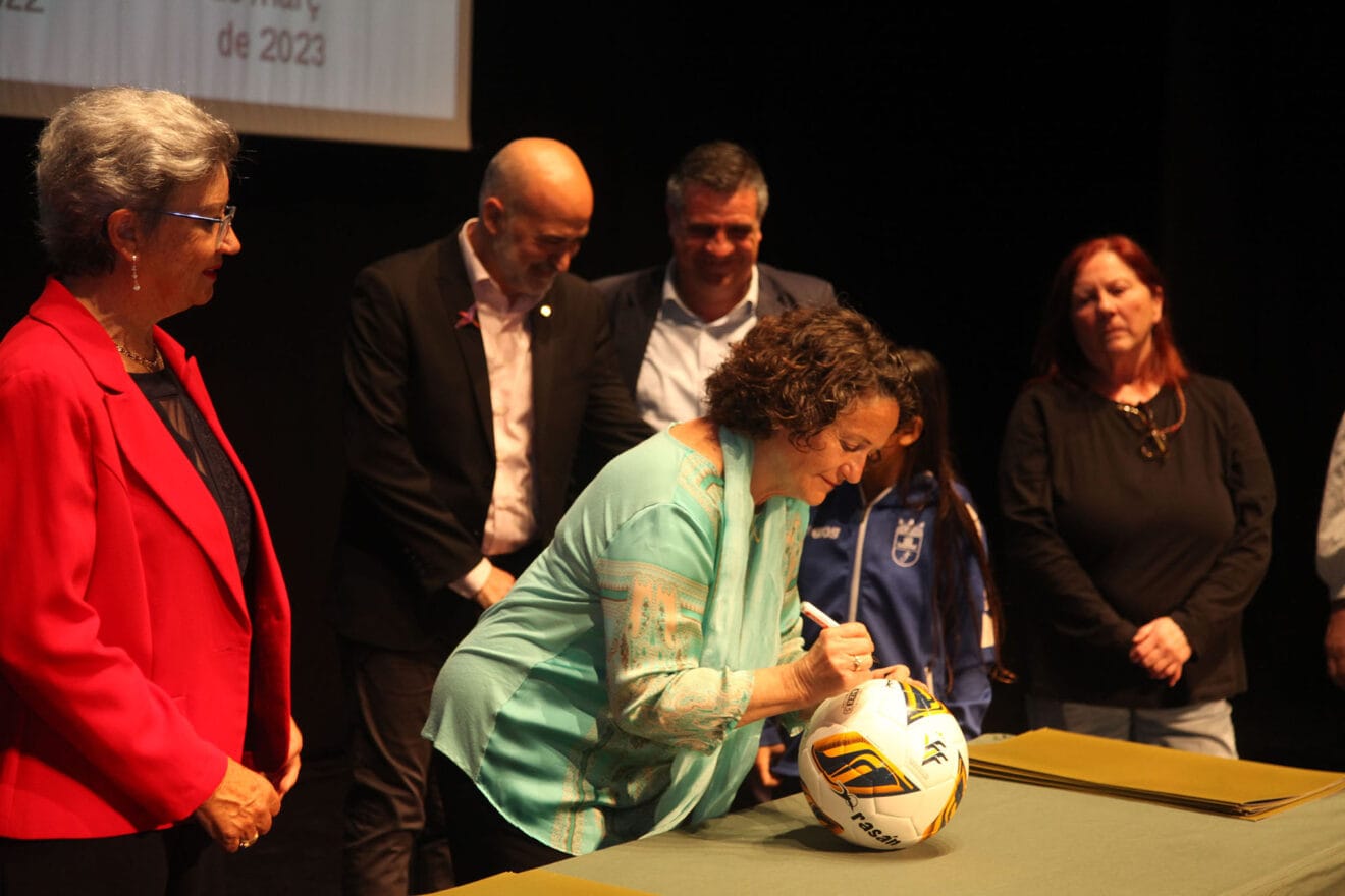 Las homenajeadas firman un balón para la escuela de fúbtol